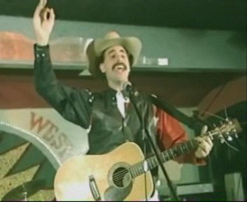 Borat playing guitar in a cowboy bar