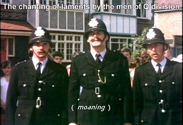 John Cleese leads the men of Q Division in the chanting of laments