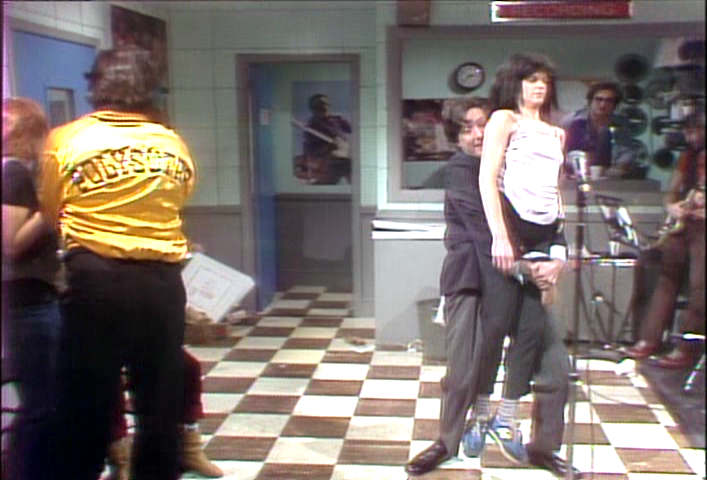 Eric Idle carries Gilda Radner to the mic