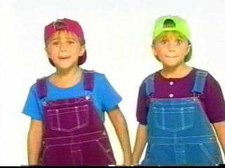 childhood image of Mary-Kate and Ashley Olsen in overall jump suits