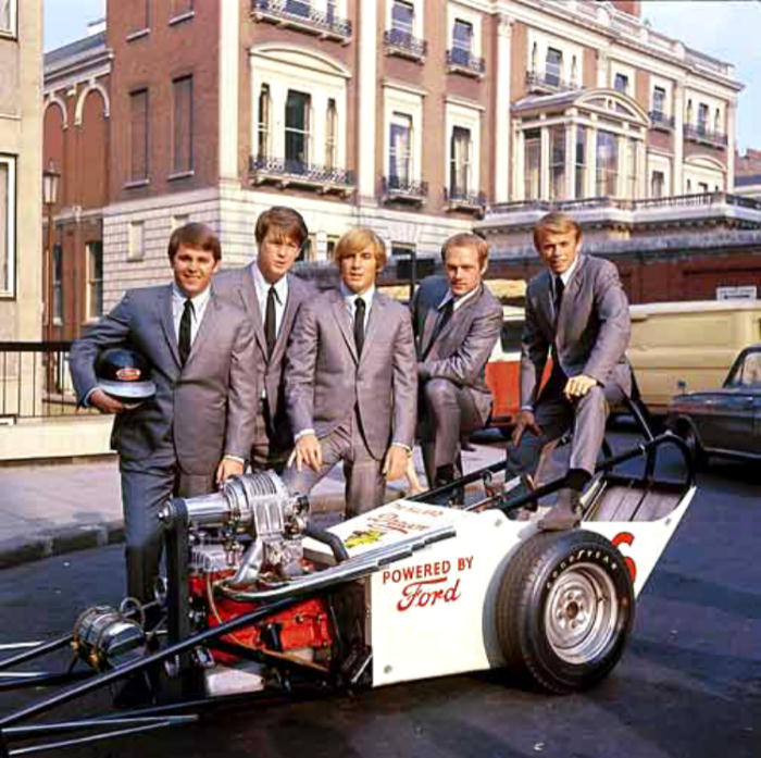 handsome young Brian Wilson and the Beach Boys with a race car