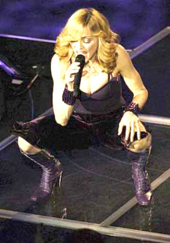 Madonna Louise Ciccone in purple boots squatting on stage