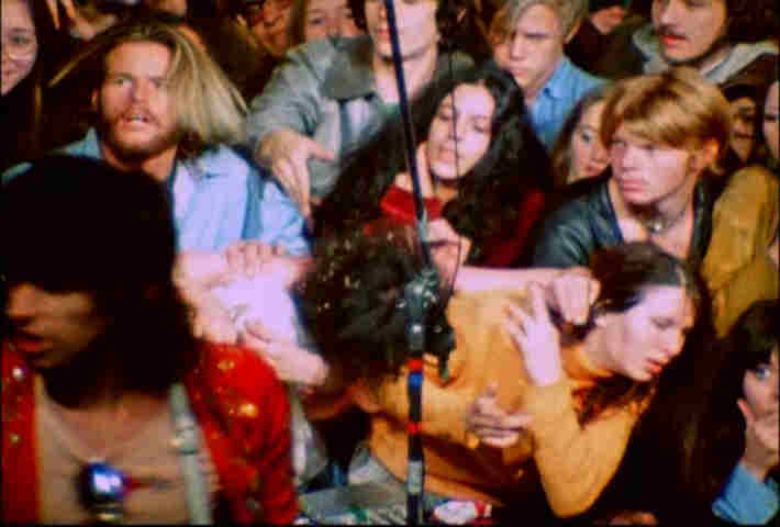 Keith Richards on stage at Altamont while fans fight in crowd