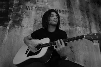 Sananda Maitreya playing an acoustic guitar