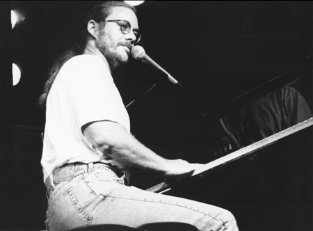 Warren Zevon with a ponytail and a piano