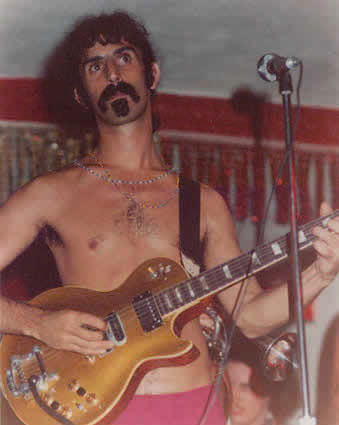 shirtless Frank Zappa playing guitar