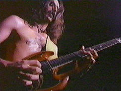 shirtless Frank Zappa playing guitar