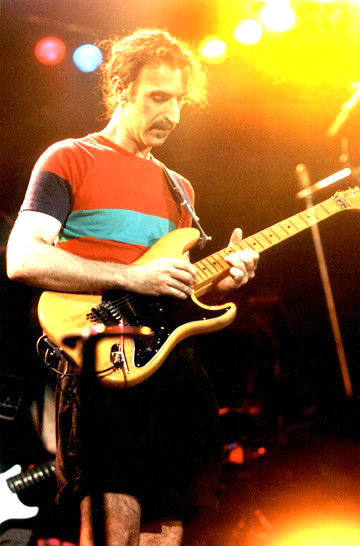 Frank Zappa playing guitar in yellow light